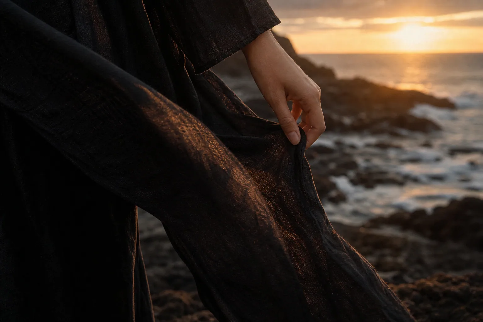 A hand and black fabric move in coastal wind.
