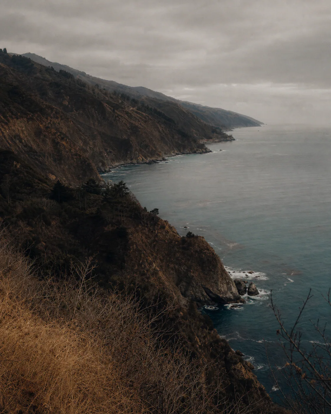 Dark cliffs face a teal sea.